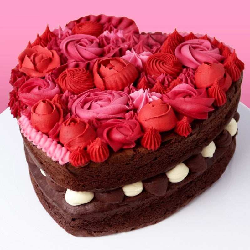 Finished example of a heart shaped chocolate cake made using the PME heart pan, decorated with piped tones of Red and Pink buttercream Rosettes