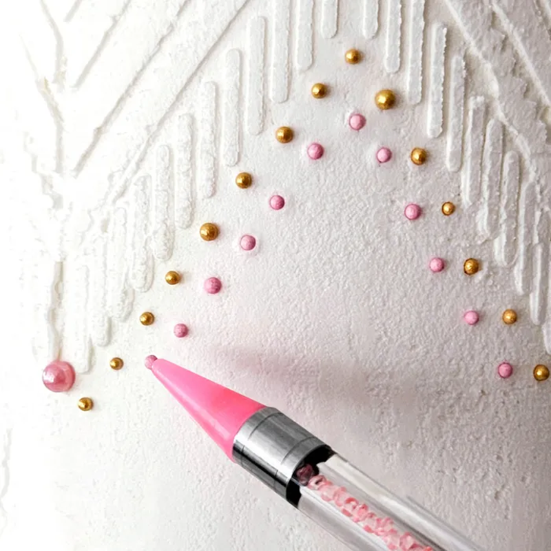 Sticky Pen placing a sugar pearl in place on icing